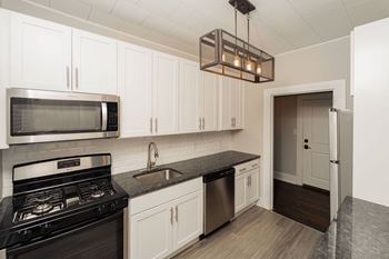 a kitchen with white cabinets and a black stove and a microwave at The Packard, West Hartford, CT